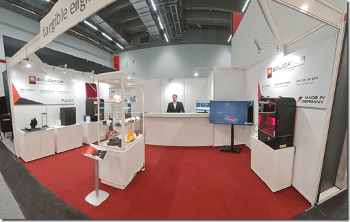 Messestand Solidator auf der Formnext 2021 mit ausgestellten 3D gedruckten Objekten wie Zahnschienen, technische CAD-Objekte und Architektur Objekte aus Harz und Resin.